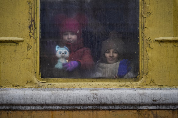 Ukrainian children look out of the window of an unheated Lviv-bound train, in Kyiv, Ukraine.