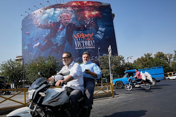 Motorcyclists in Tehran pass a billboard depicting Donald Trump with the words: “Great Victory! Strait of Hormuz.”