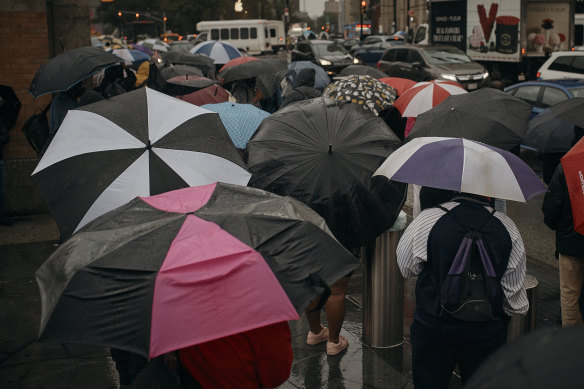 People wait for the bus as trains get cancelled due to flooding from heavy rains.