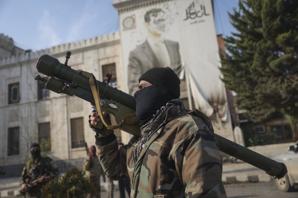 A Syrian opposition fighter holds a rocket launcher in front of the provincial government office.