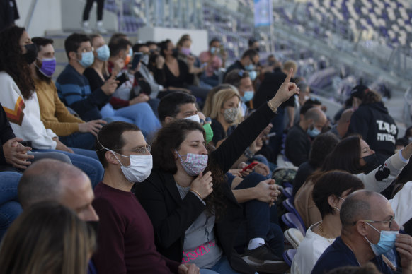 Concert-goers in Tel Aviv enjoy a performance at a soccer stadium after presenting proof of vaccination via their “green passport” - available on an app or as a printed tag.