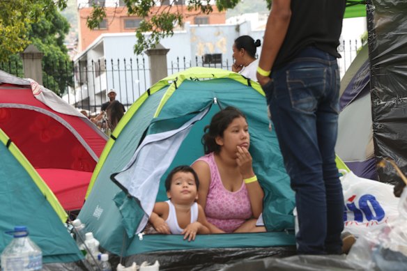Residents of a damaged building sit beside belongings as they take shelter on a street after a magnitude 7.2 earthquake struck Venezuela and other regions in the Caribbean on June 28.