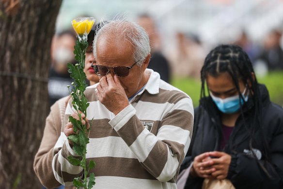 Mourners becoming emotional as they lay flowers for the victims of the Tai Po fire.