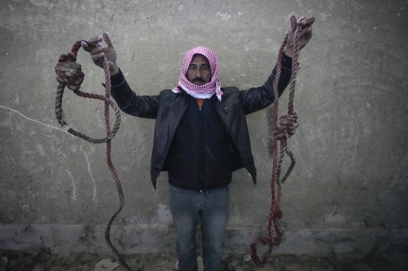 A man holds up two ropes tied in the shape of nooses, found in the infamous Sednaya military prison.