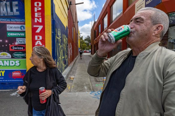 A man and a woman drink and smoke on the streets of Footscray.
