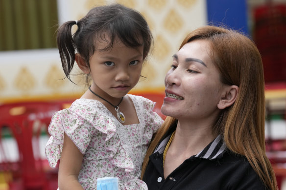 Paweenuch Supolwong, 3, the only child to emerge unscathed from the mass killing attack at the day care center, is held by her mother Anonpai Srithong, 35.