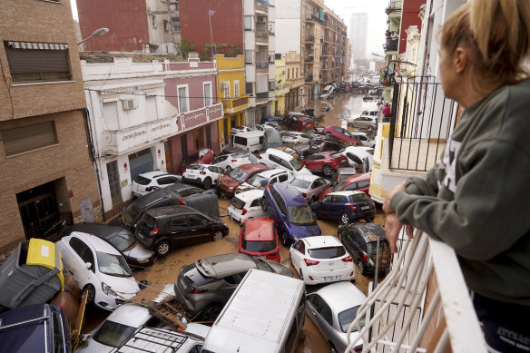A woman looks out from her balcony as vehicles are trapped in the street after flooding in Valencia in October.