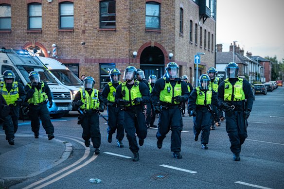 Police officers run at protesters near the Bell Hotel in Epping on Sunday.