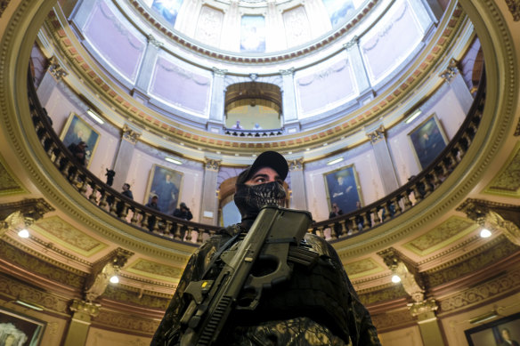 An armed protester wearing a mask stands at the Michigan Capitol Building in Lansing, Michigan.