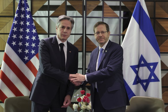 US Secretary of State Antony Blinken, left, and Israeli President Isaac Herzog shake hands.