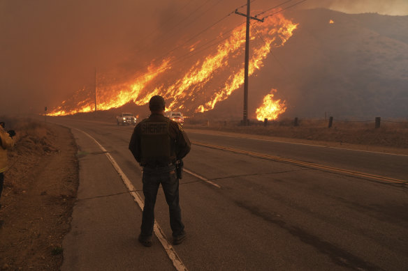 Los Angeles County Sheriff’s deputy monitors flames caused by the Hughes Fire along Castaic Lake in Castaic, California.