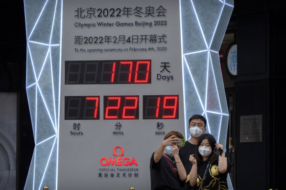 People take selfies in front of a display showing a countdown clock to the 2022 Winter Olympics in Beijing.