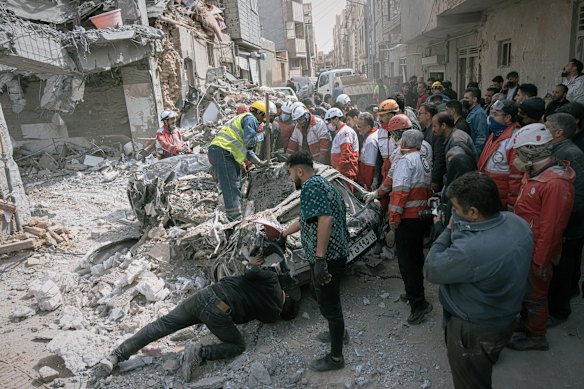First responders inspect a destroyed car at the site of a US-Israel strike on a residential building in Tabriz, north-western Iran.