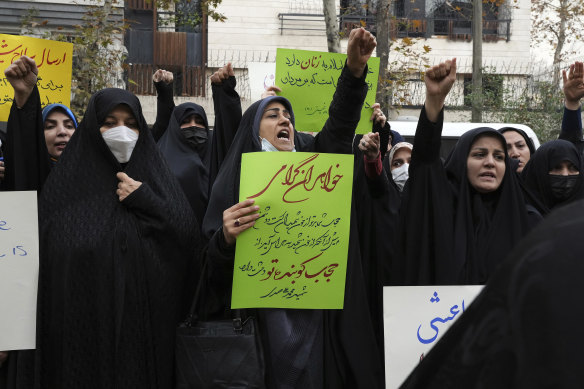 A group of pro-government demonstrators chant slogans as one of them holds a poster encouraging women to wear Islamic hijab in a gathering in front of the United Nation’s office in Tehran in December.