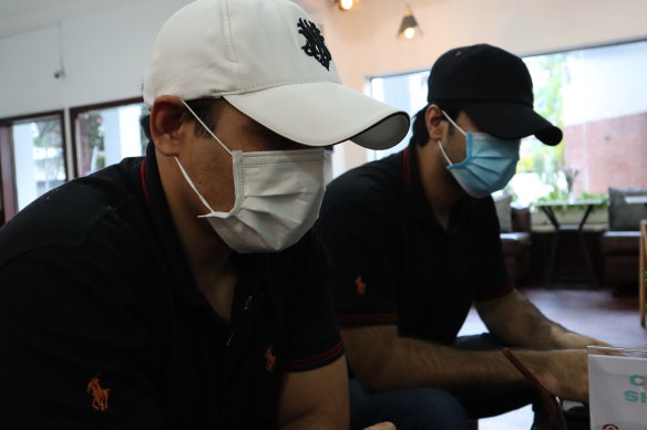 Ali* (left) wears a white cap and his cousin (right) escaped a razor wire protected compound in Cambodia where they were forced to scam people online.