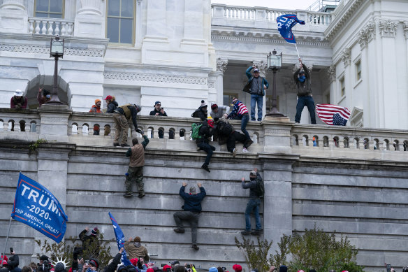 Supporters of President Donald Trump climb the west wall of the the US Capitol.