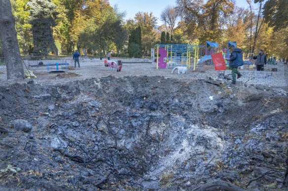 A man passes a rocket crater at a playground in Kyiv following Monday’s attacks.