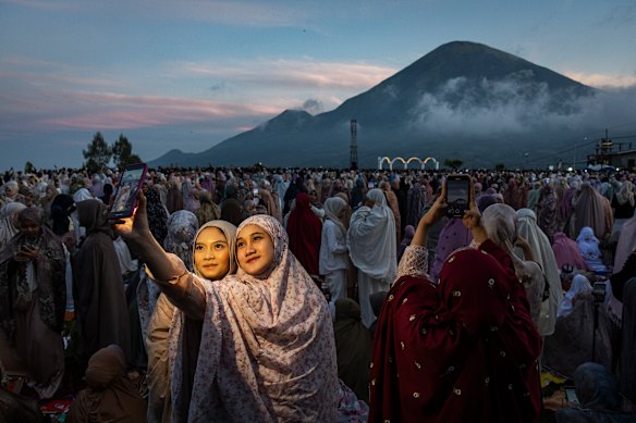 Indonesian Muslims take selfies with Mount Sindoro in the background as they attend Eid al-Adha prayers at Butuh village in Wonosobo, Central Java, Indonesia.