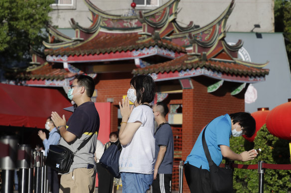 People wear face masks to protect against the spread of the coronavirus and pray outside Hsing Tian Kong Temple in Taipei, Taiwan.