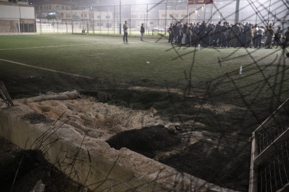 Residents gather with authorities at a soccer field that was hit by a rocket, killing multiple children and teenagers, in the Druze town of Majdal Shams.