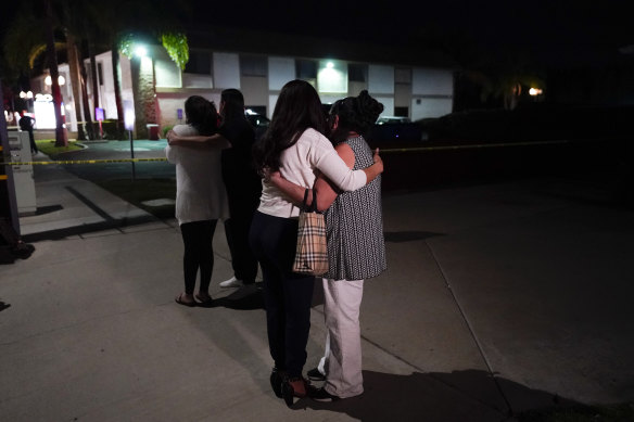 People comfort each other as they stand near the building where four people, including a child, were killed in Orange, California.