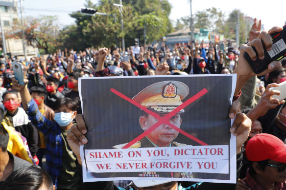 A protester holds a placard with a defaced image of Myanmar military commander-in-chief Senior General Min Aung Hlaing.