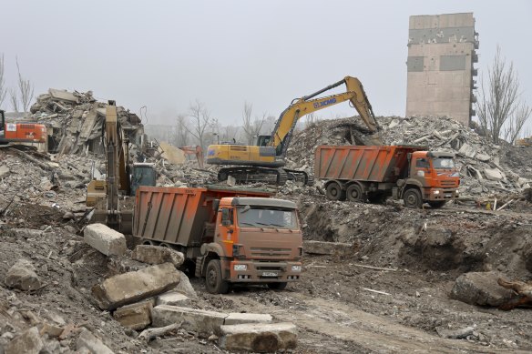 Municipal workers clear rubble and disassemble destroyed buildings after heavy fighting at Mariupol theater in Mariupol on Saturday.