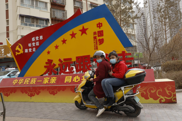 A sign displays slogans “China’s ethnicities, one family” and “Forever follow the party” in Aksu, Xinjiang.
