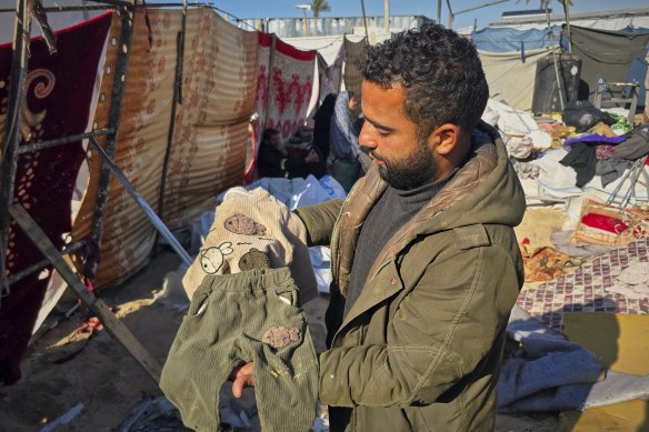 Alaa Abu Helal shows clothes of his 13-month-old son, Mohammed, before Mohammed and his pregnant mother, Afana, are buried in Khan Younis. They were killed by Israeli airstrikes on Tuesday.