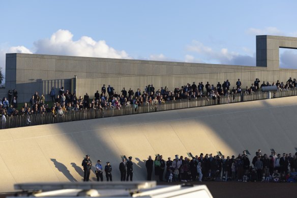 People gather at Parliament House to watch the 96-gun salute.