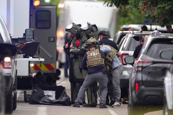 Law enforcement officials dress in protective gear to investigate after an attack in Boulder.