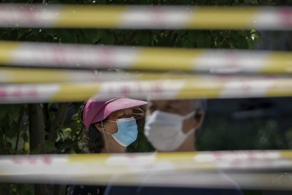 Residents wearing face masks line up behind barricaded tapes for COVID mass testing near a residential area in Beijing. 