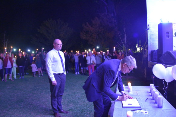 Moira Administrator John Tanner signs the condolence book on Wednesday at a vigil for the five people killed in the Strathmerton crash as Moira Shire acting chief executive Joshua Lewis looks on. 