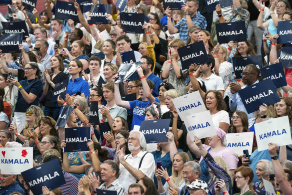 Democrats hold up signs in support of Vice President Kamala Harris as she campaigns for president.