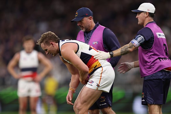 Jordan Dawson of the Crows receives treatment after a hit to the ribs. 
