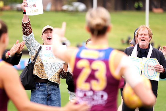 The Lions cheer squad hold up signs for AFLW player Eleanor Hartill in her 50th game.