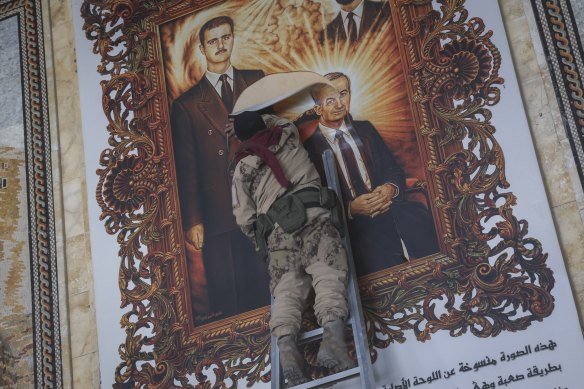 A Syrian opposition fighter tears up a painting depicting Syrian President Bashar al-Assad and his late father, Hazef al-Assad, at the Aleppo international airport.