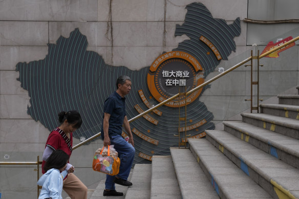 Residents walk past a map showing Evergrande development projects in China.