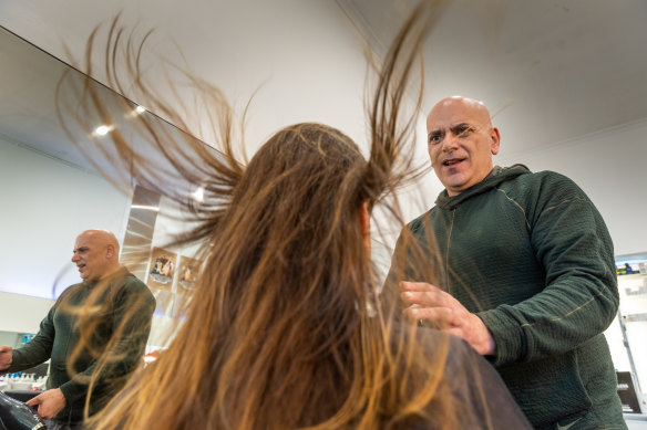 Roland Semaarn dries the hair of Maree, a single mother of two young girls who had not had a professional haircut for two years and says she left his salon “feeling beautiful”.