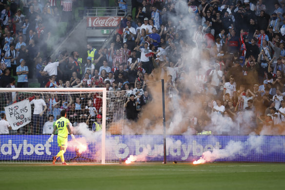 Melbourne Victory's Paul Izzo removes the flare from the pitch after a Melbourne City goal.