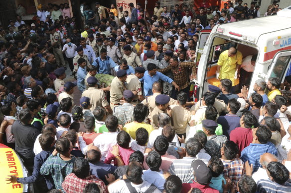 A victim is carried towards an ambulance after a structure covering a well in an Indian temple collapsed.