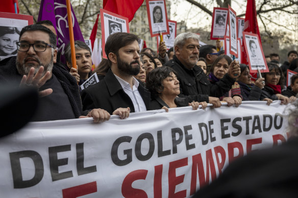Chilean President Gabriel Boric (third from left) takes part in a march remembering the victims of the 1973 military coup. Soon after, sections of the crowd clashed violently with police.