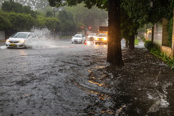 Motorists drive through localised flooding on Mona Vale Road in St Ives on Sunday morning.