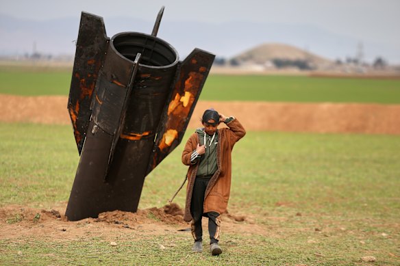 A shepherd boy walks away from an unexploded Iranian projectile that landed in an open field in eastern Syria.