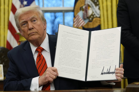 Trump holds up the executive order outlining the steel and aluminium tariffs.