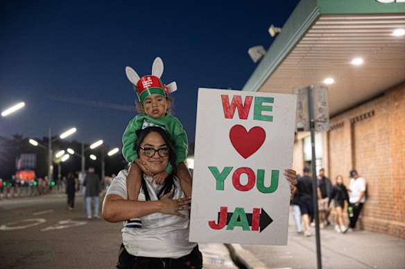 Rachel Adams with Te Wairua Mete, 3, show a sign in support of Jai Arrow at Allianz Stadium.