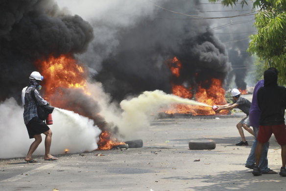 Anti-coup protesters extinguish fires during a protest in Thaketa township Yangon, Myanmar.