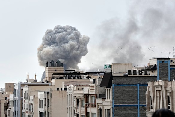 A plume of smoke rises after a strike in Tehran on Monday.