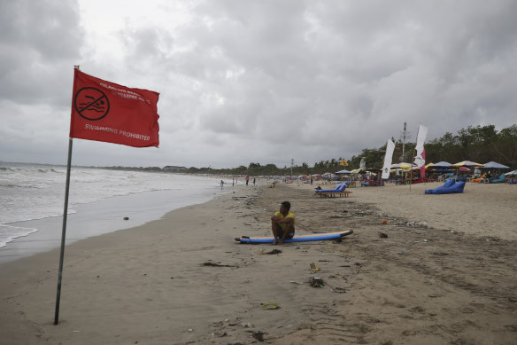 A man sits on a surfboard at Kuta beach in Bali, Indonesia, on Thursday. A hoped-for boom in Chinese tourism in Asia over next week’s Lunar New Year holidays looks set to be more of a blip.