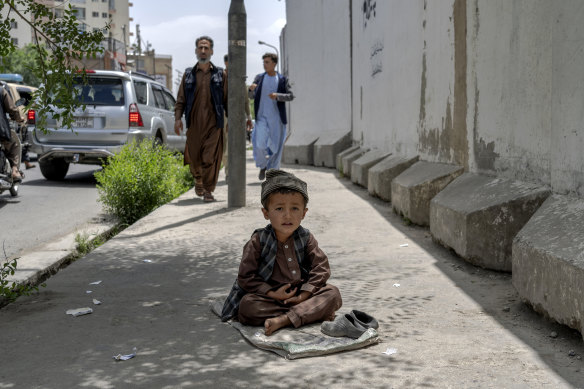 A child begs on a footpath in Kabul, Afghanistan, in May.
